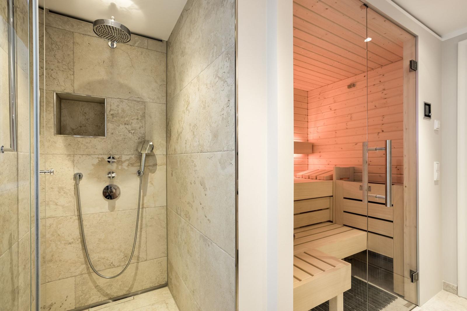Dusche mit Steinwand und Sauna mit Holzbank.