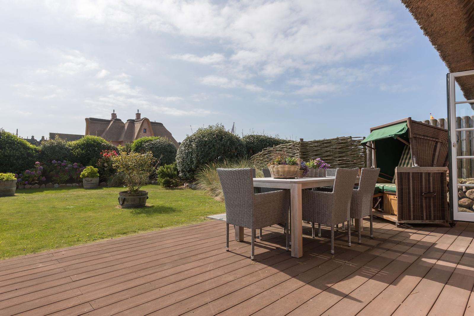 Terrasse mit Esstisch, Garten und Blick auf traditionelle Häuser.