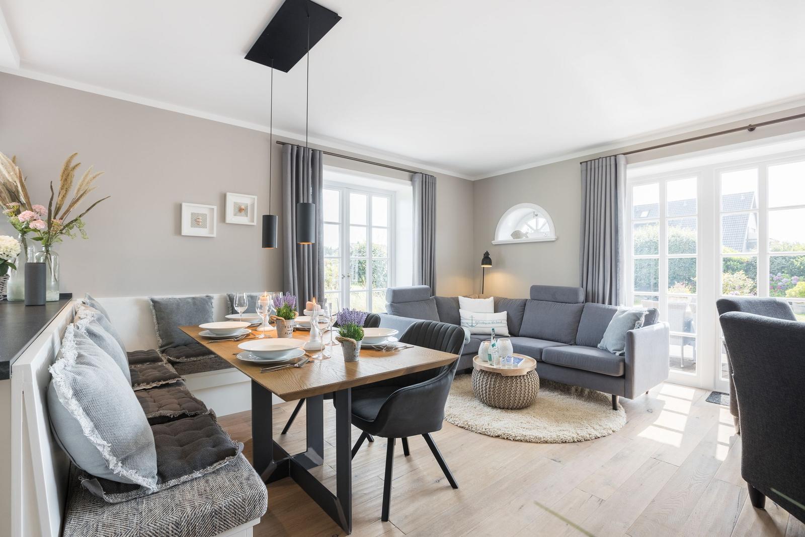 Essbereich mit Tisch und Stühlen, Wohnbereich mit Sofa und Fenster.
