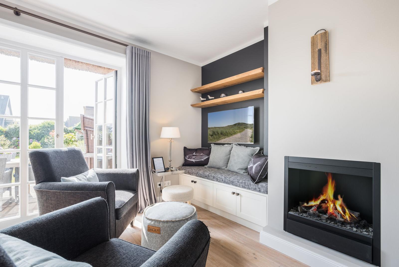 Wohnzimmer mit Kamin, Sitzbank und Fenster zur Terrasse.