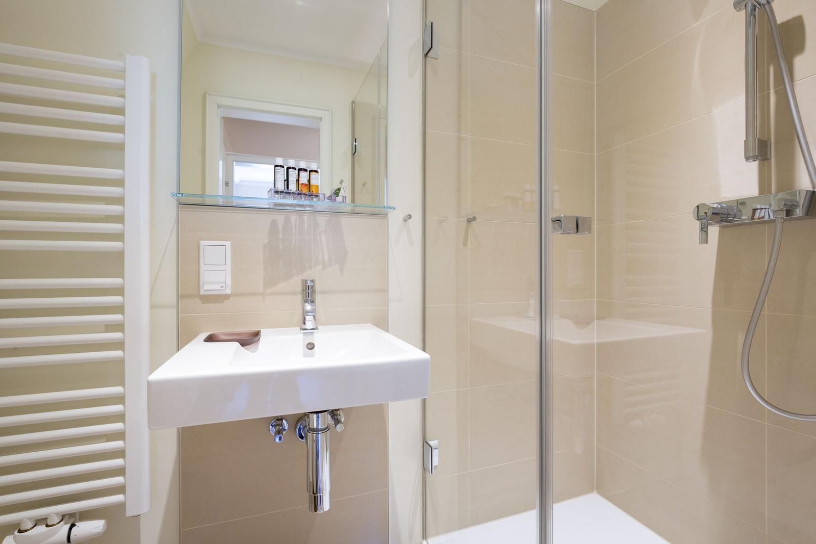 Badezimmer mit Dusche, Waschbecken und Heizkörper