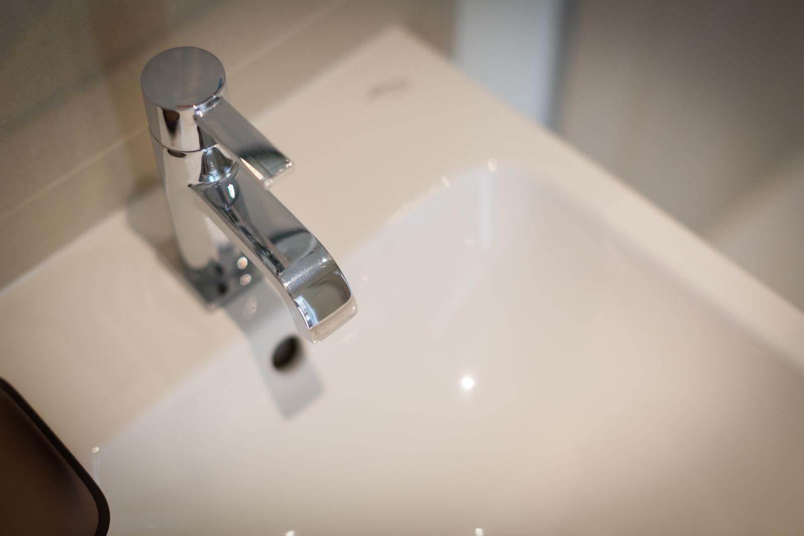Moderne Waschbecken mit chromfarbenem Wasserhahn und glatter Oberfläche.