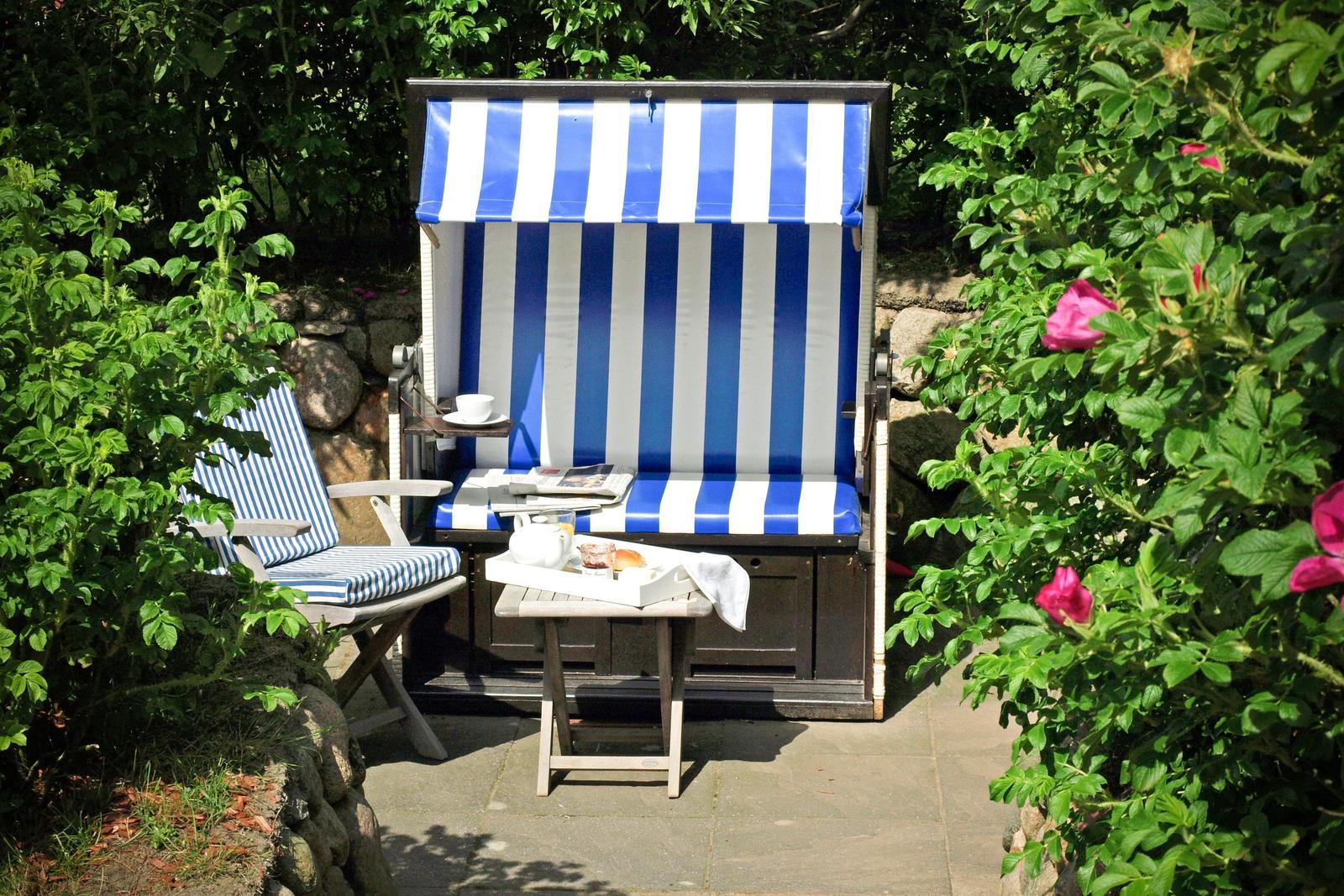 Blau-weiße Strandliege mit Tisch und Stühlen im Garten.
