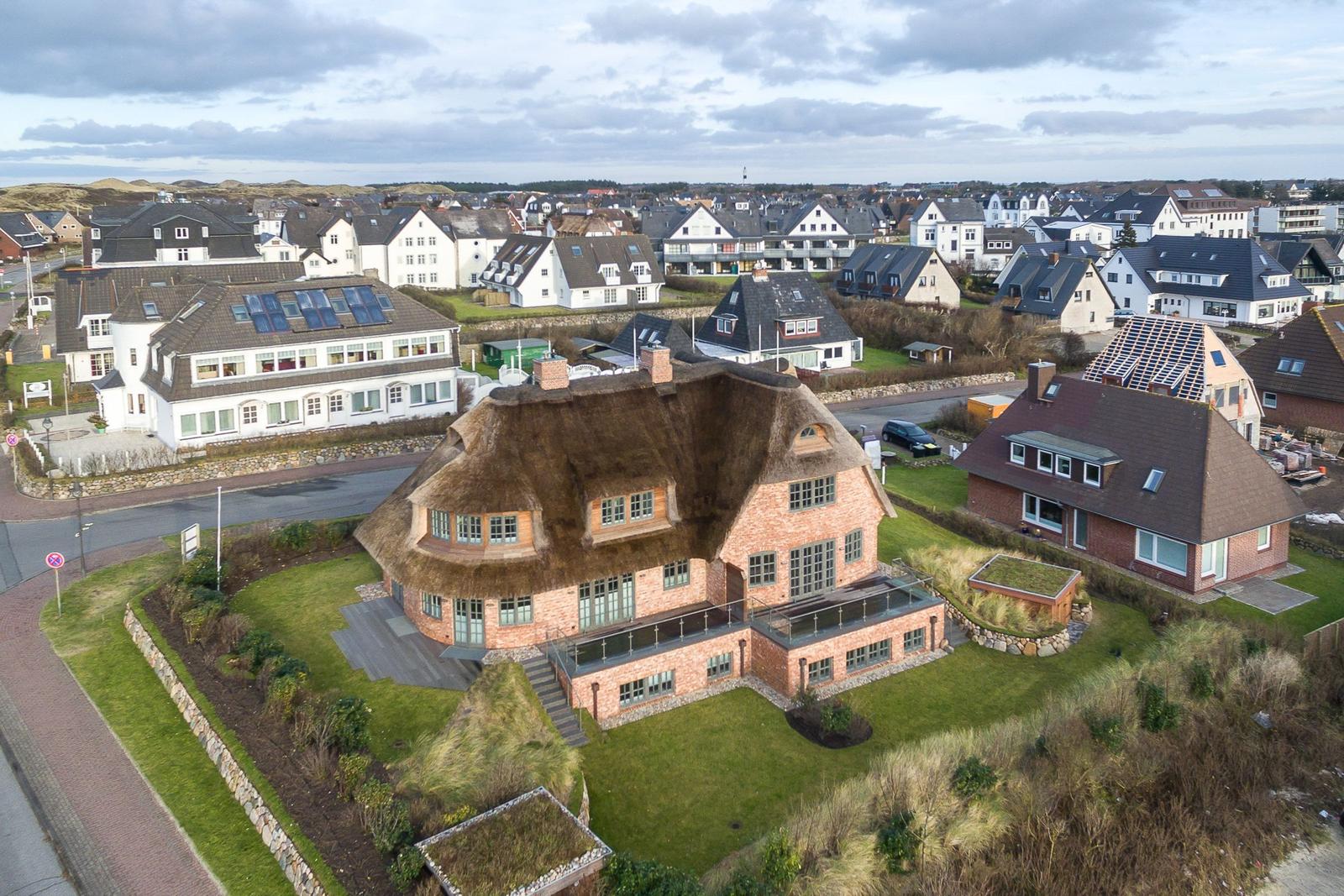 Village house with thatched roof and terrace in quiet residential area.