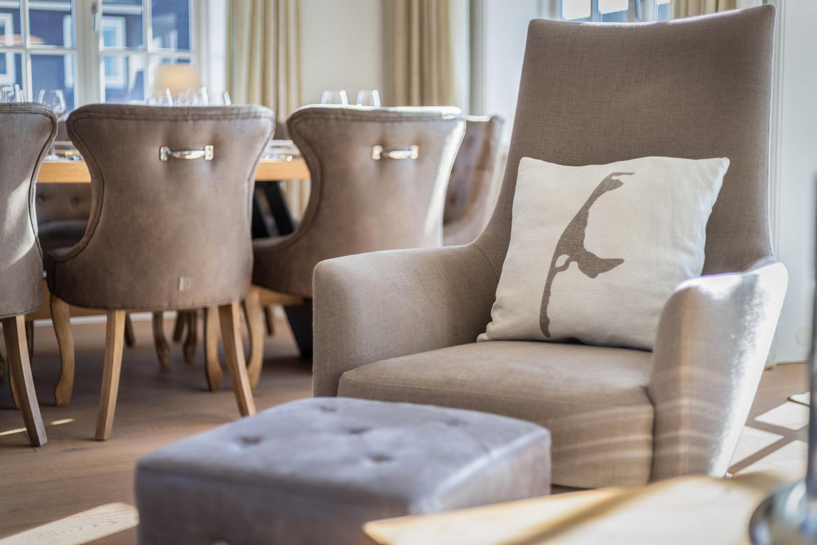 An armchair with a cushion and a table with chairs in the room.