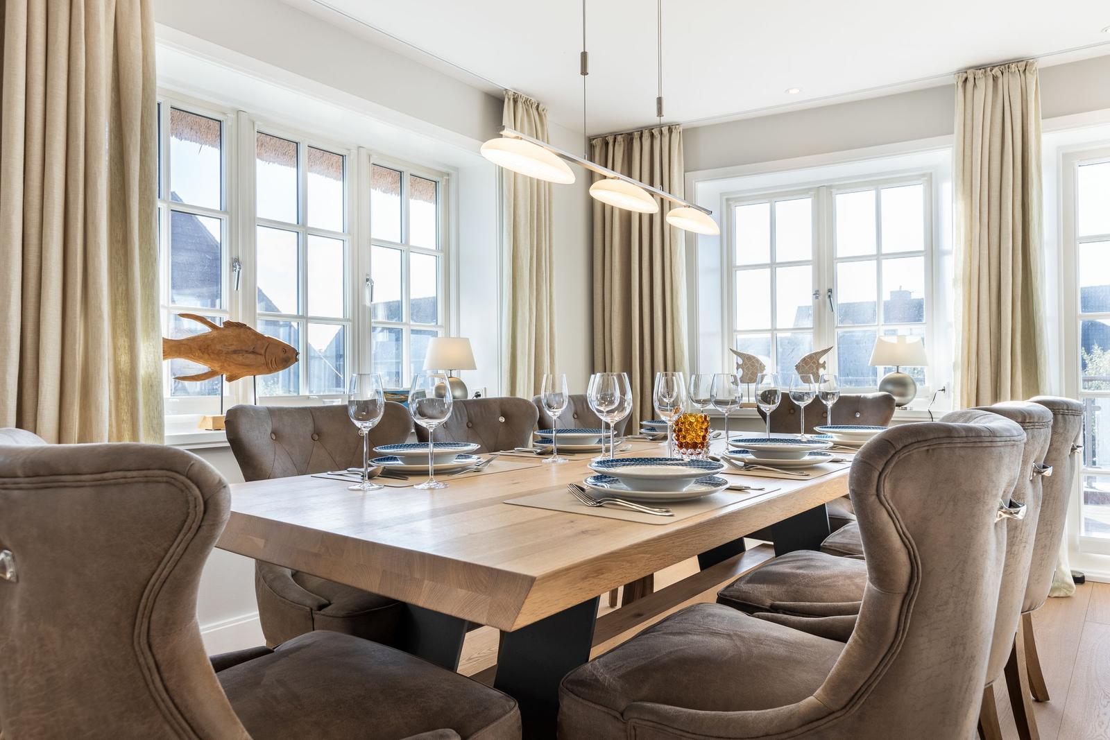 Dining room with wooden table, chairs, and windows with curtains.