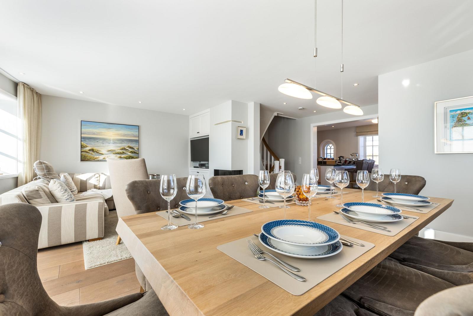 Dining room with set table, living area, and staircase in background.