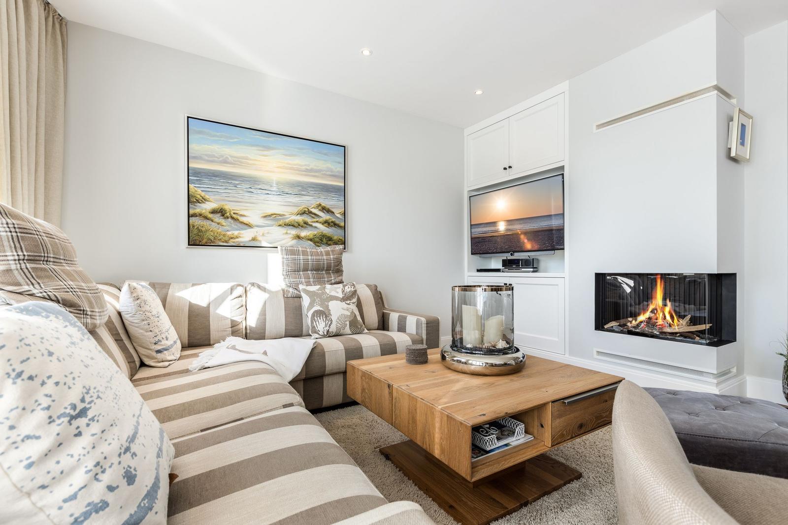 Living room with sofa, fireplace, and TV mounted on the wall.