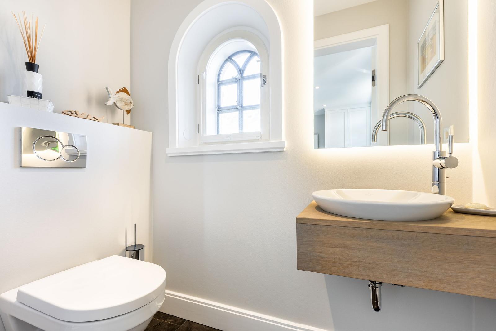Bathroom with sink, toilet, and arched window.