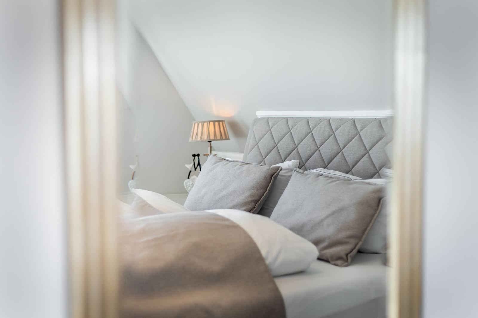 Bedroom with bed, pillows, and bedside lamp under sloped ceiling