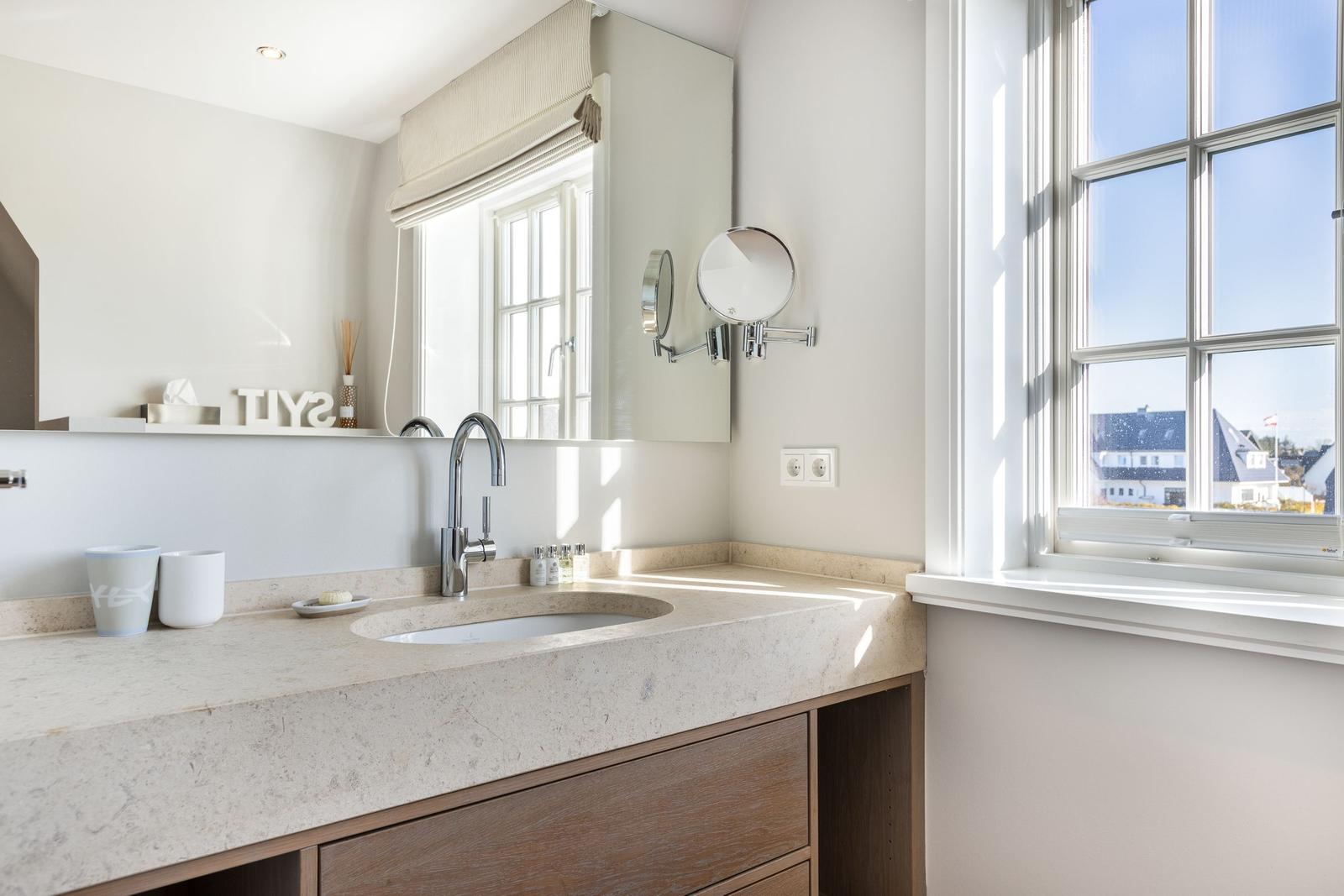 Bathroom with sink, mirror, and window with view.