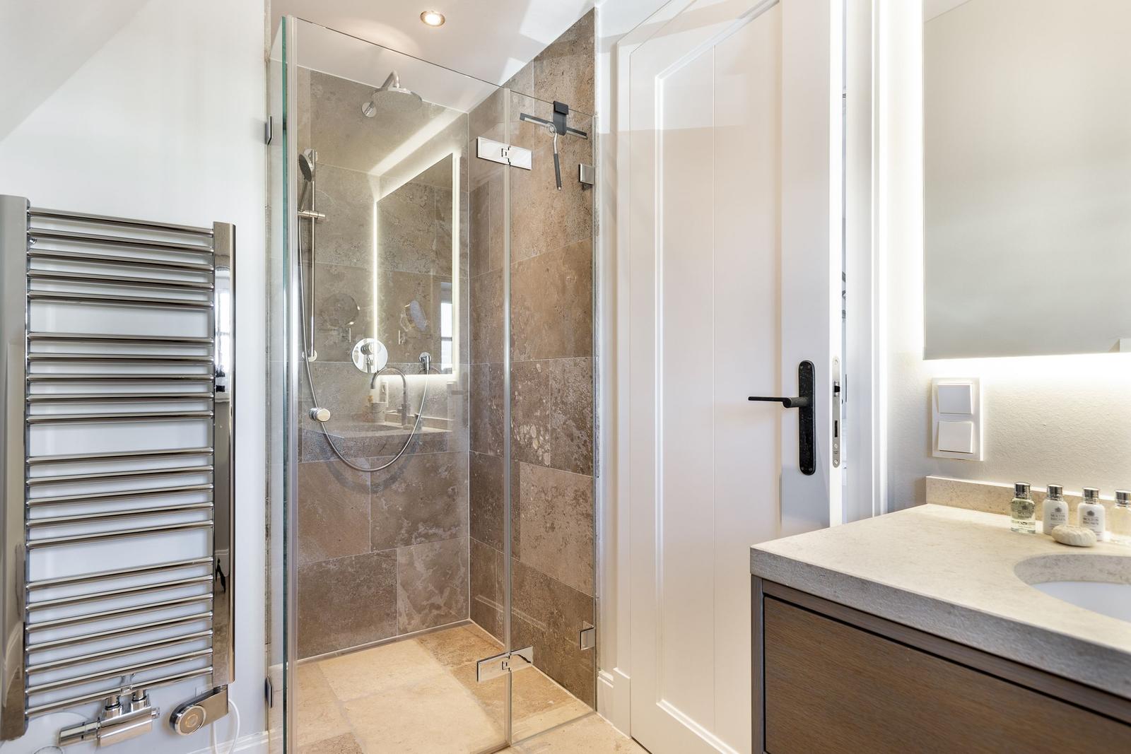 Shower cabin with glass enclosure, bathtub, and sink with mirror.