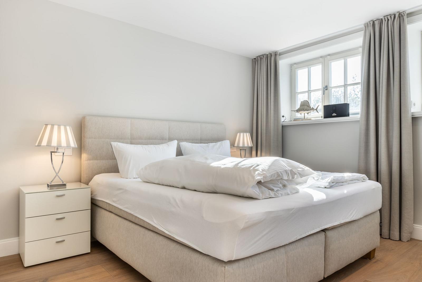 Bedroom with bed, nightstand, and window with curtains.