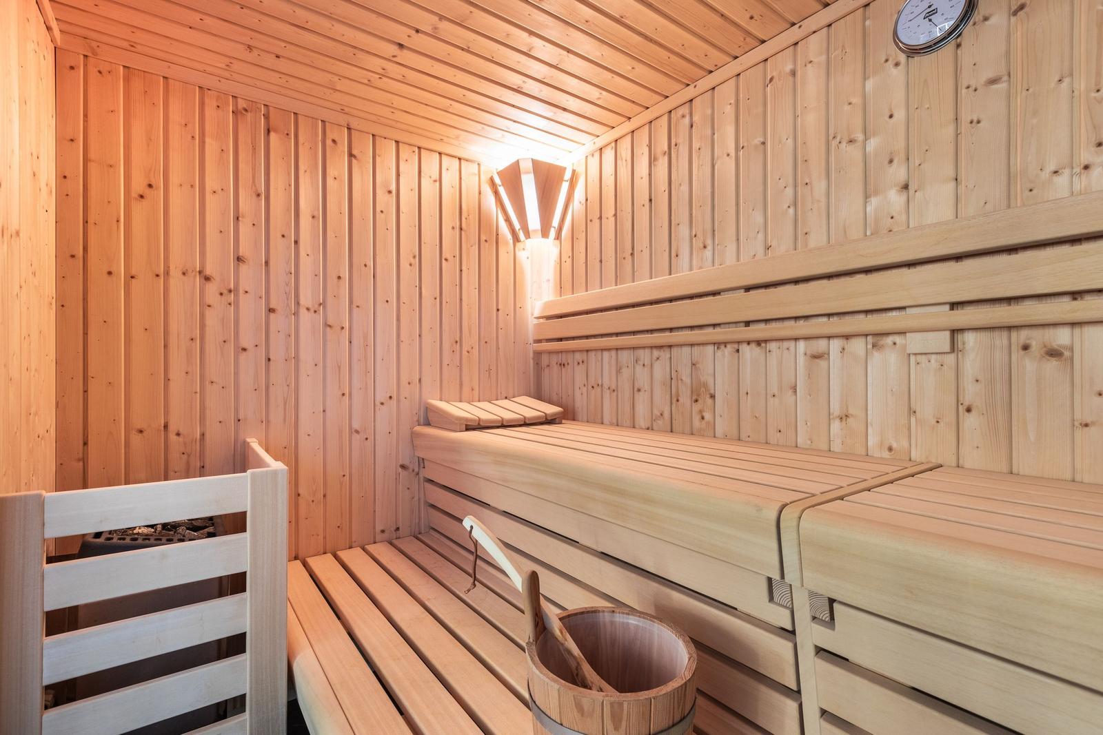 Wooden sauna with benches and water bucket.