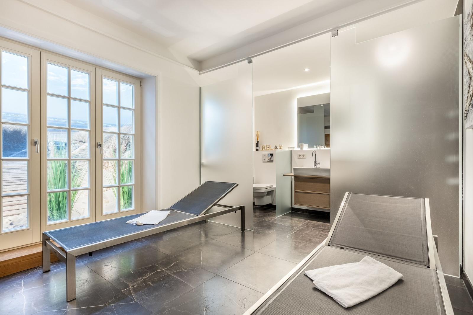 Bath with loungers and sea view through windows