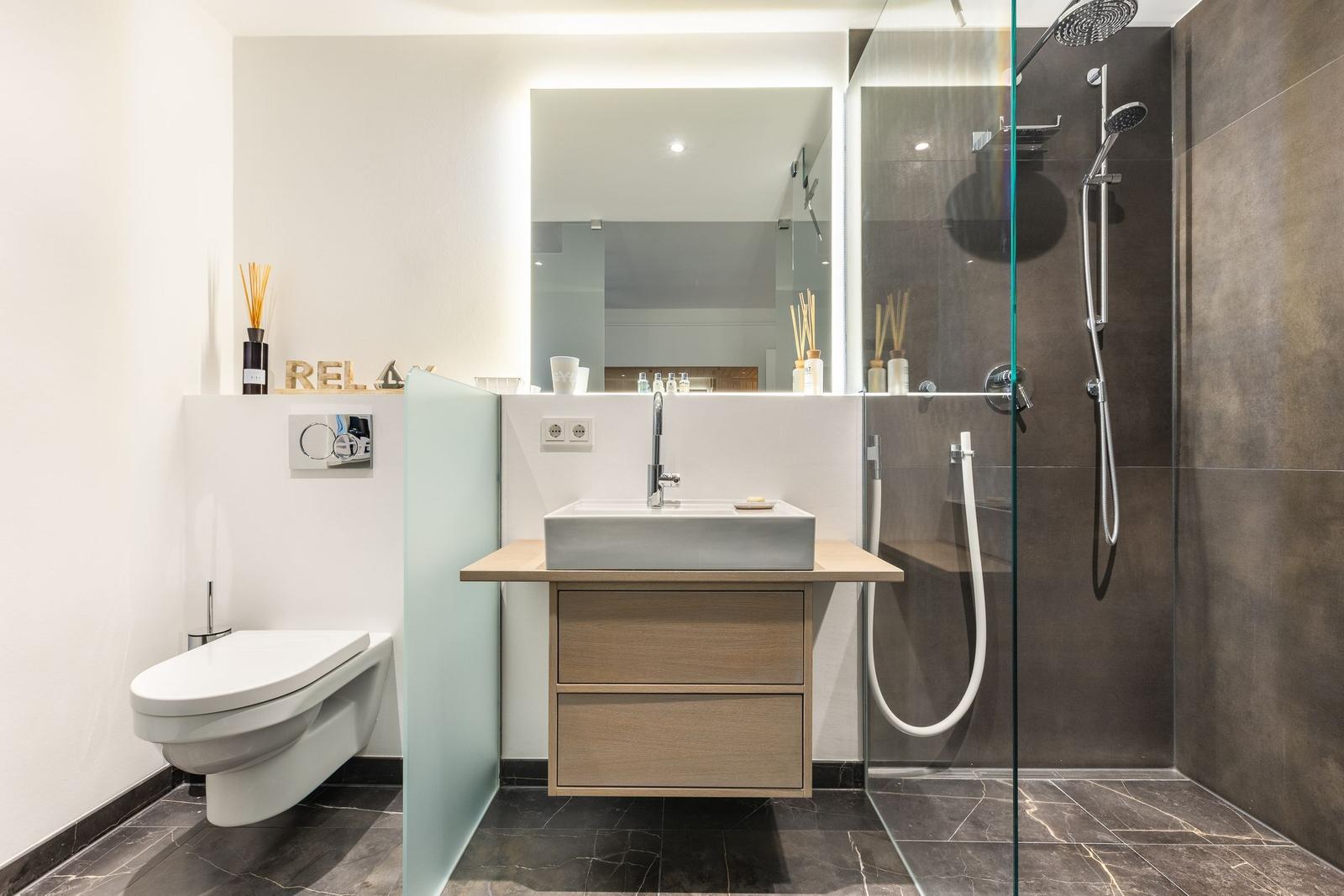 Bathroom with shower, sink, and toilet. Modern furnishings.
