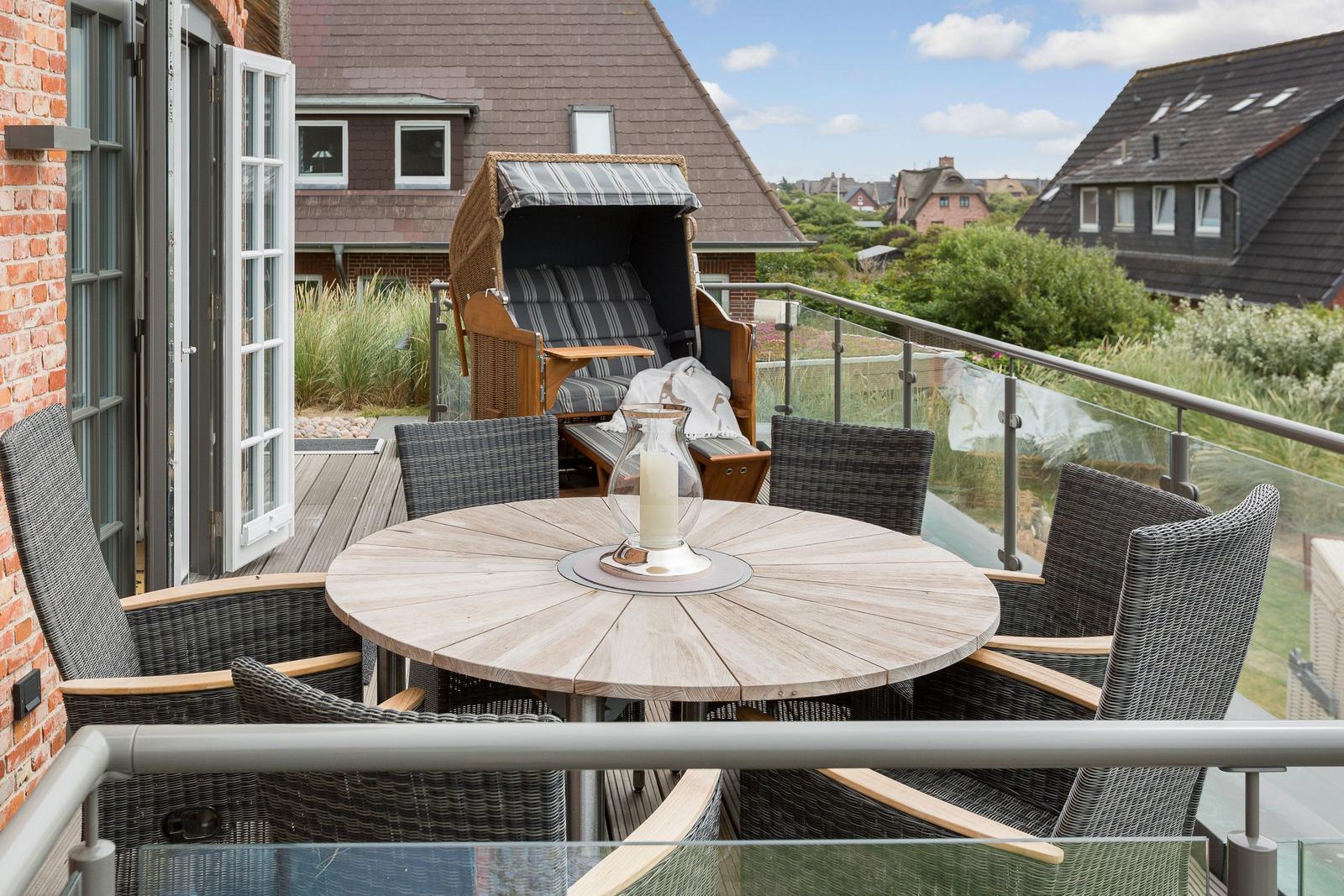 Terrace with round table and chairs, lounge chair, and view of rooftops.