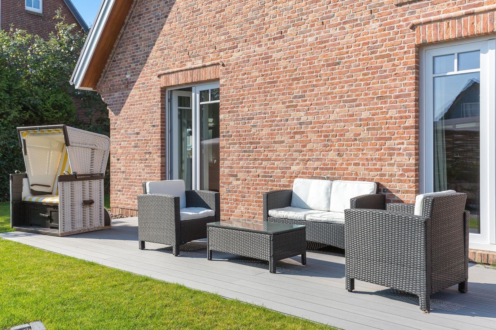 Terrasse mit Sitzgruppe und Liegestuhl vor Backsteinhaus