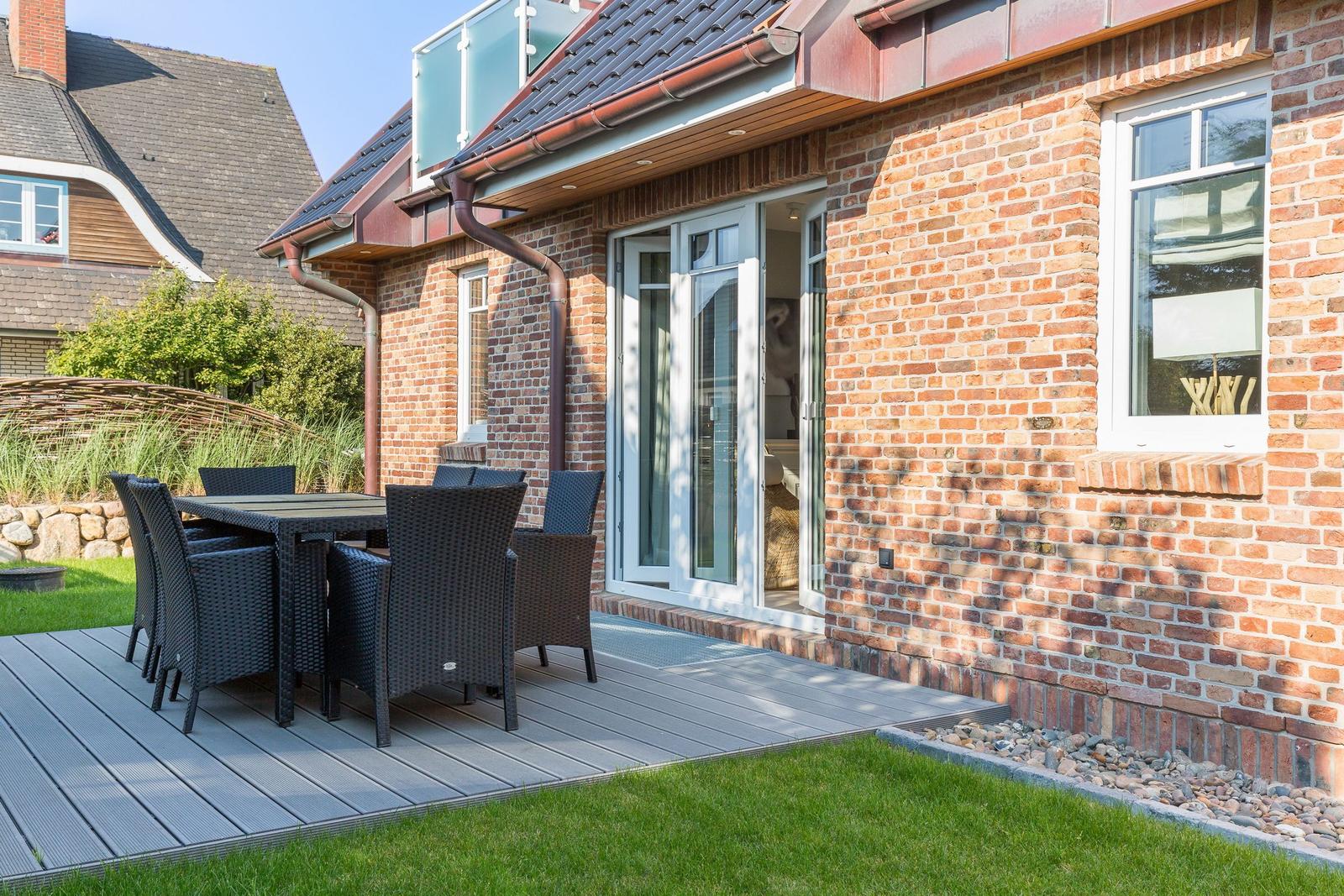 Terrasse mit Tisch und Stühlen neben einem Haus mit Backsteinfassade.