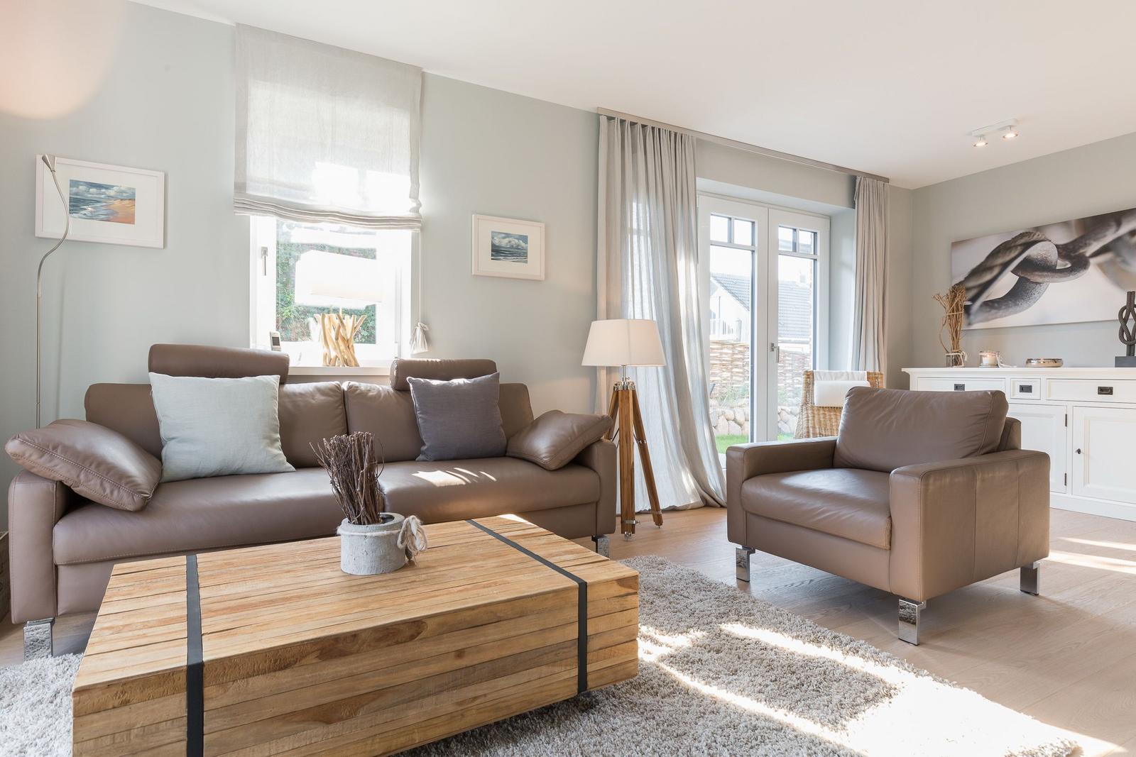 Wohnzimmer mit Ledersofa, Holztisch und Blick auf den Garten.