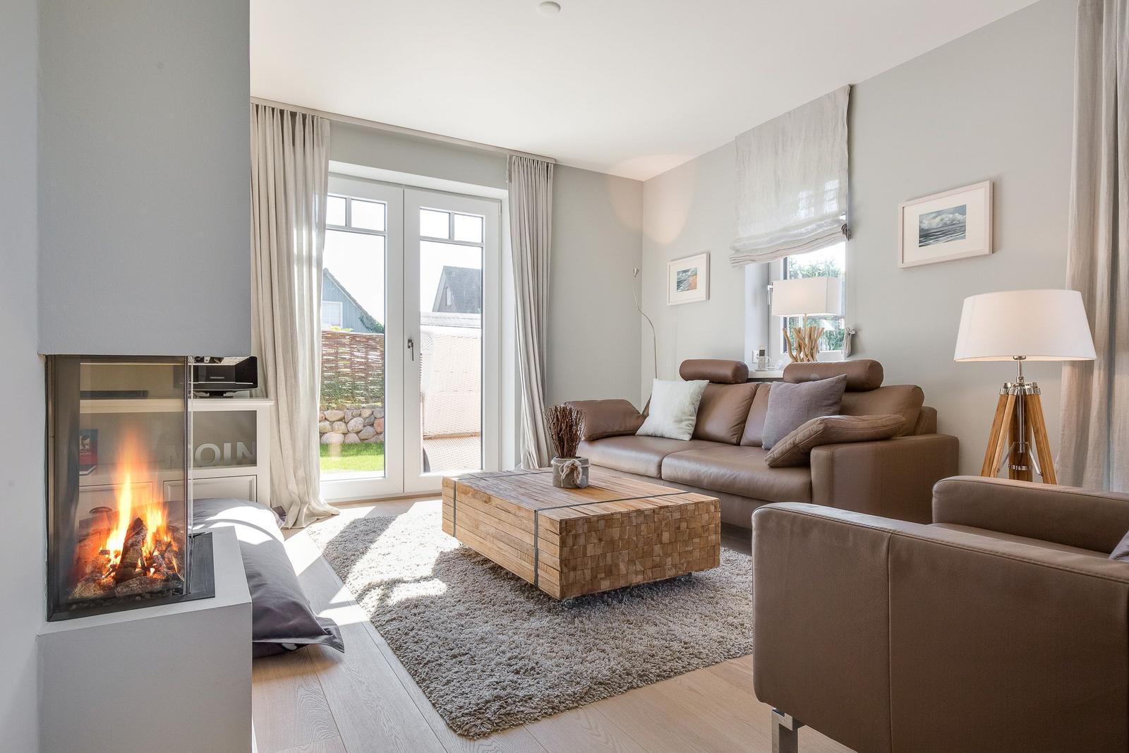 Wohnzimmer mit Sofa, Kamin und Terrassentür.