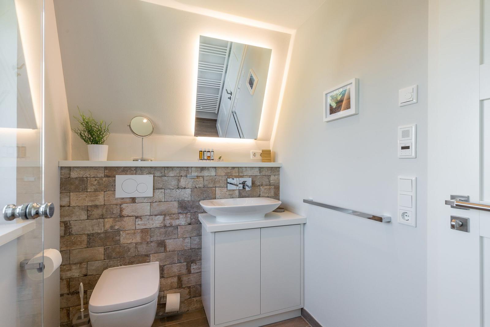 Bathroom with sink, toilet, and lit mirror