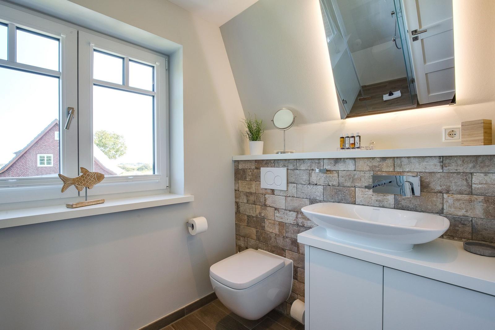 Bathroom with sink, toilet, and window with view.