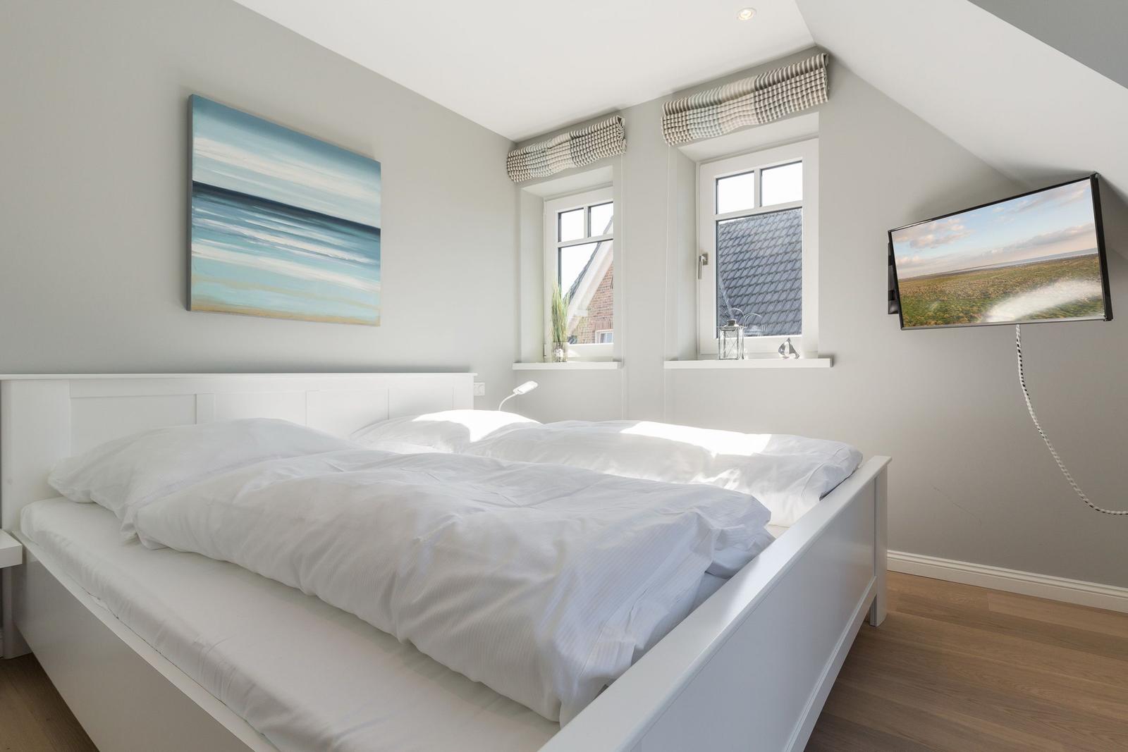 Bedroom with double bed, two windows, and wall art.