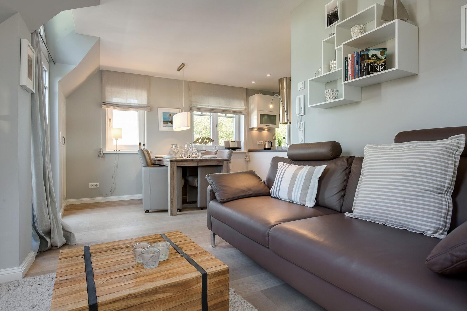 Living and dining area with sofa, table, and kitchenette.