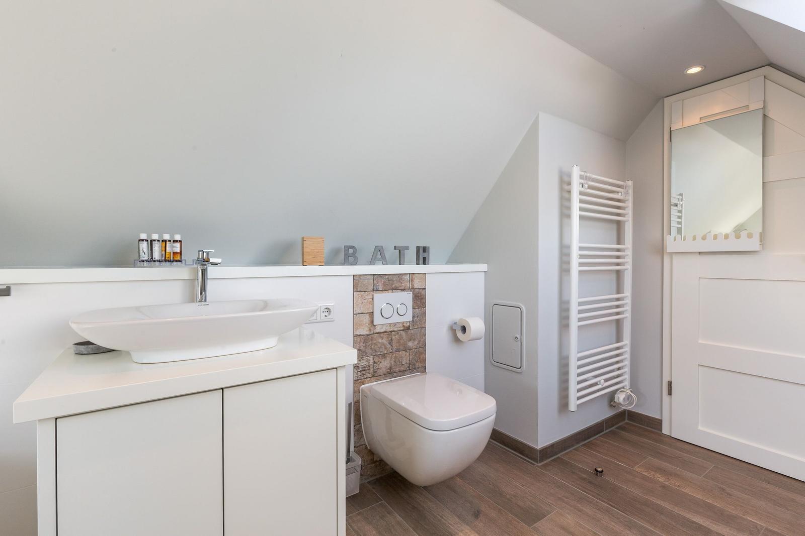 Bathroom with sink, toilet, and radiator.