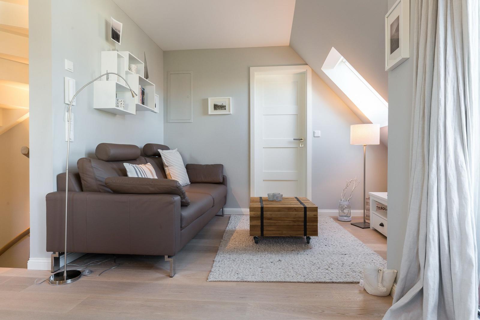 Living room with brown sofa, wooden table, and sloped ceiling.