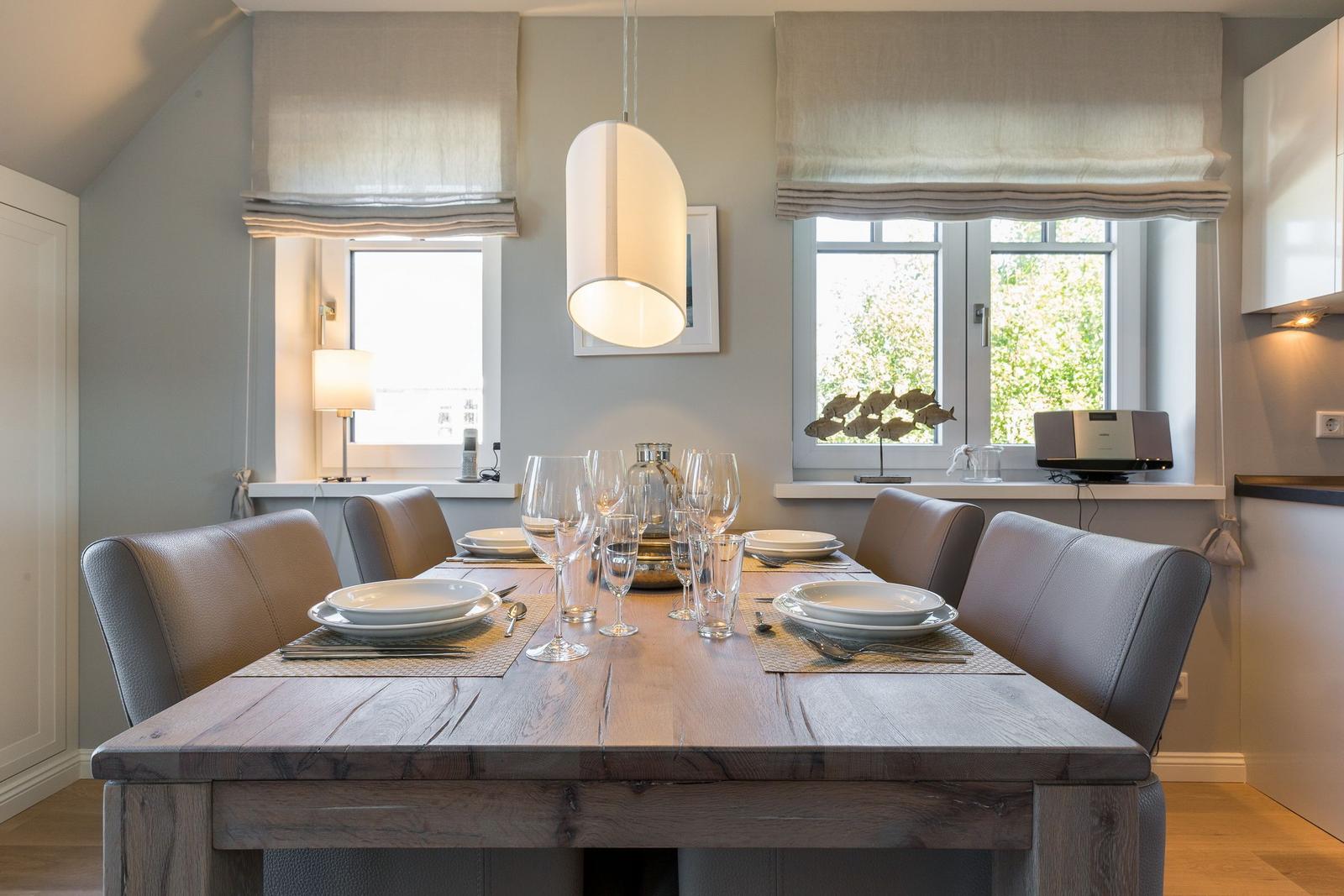 Dining room with wooden table, chairs, and windows with roller blinds.