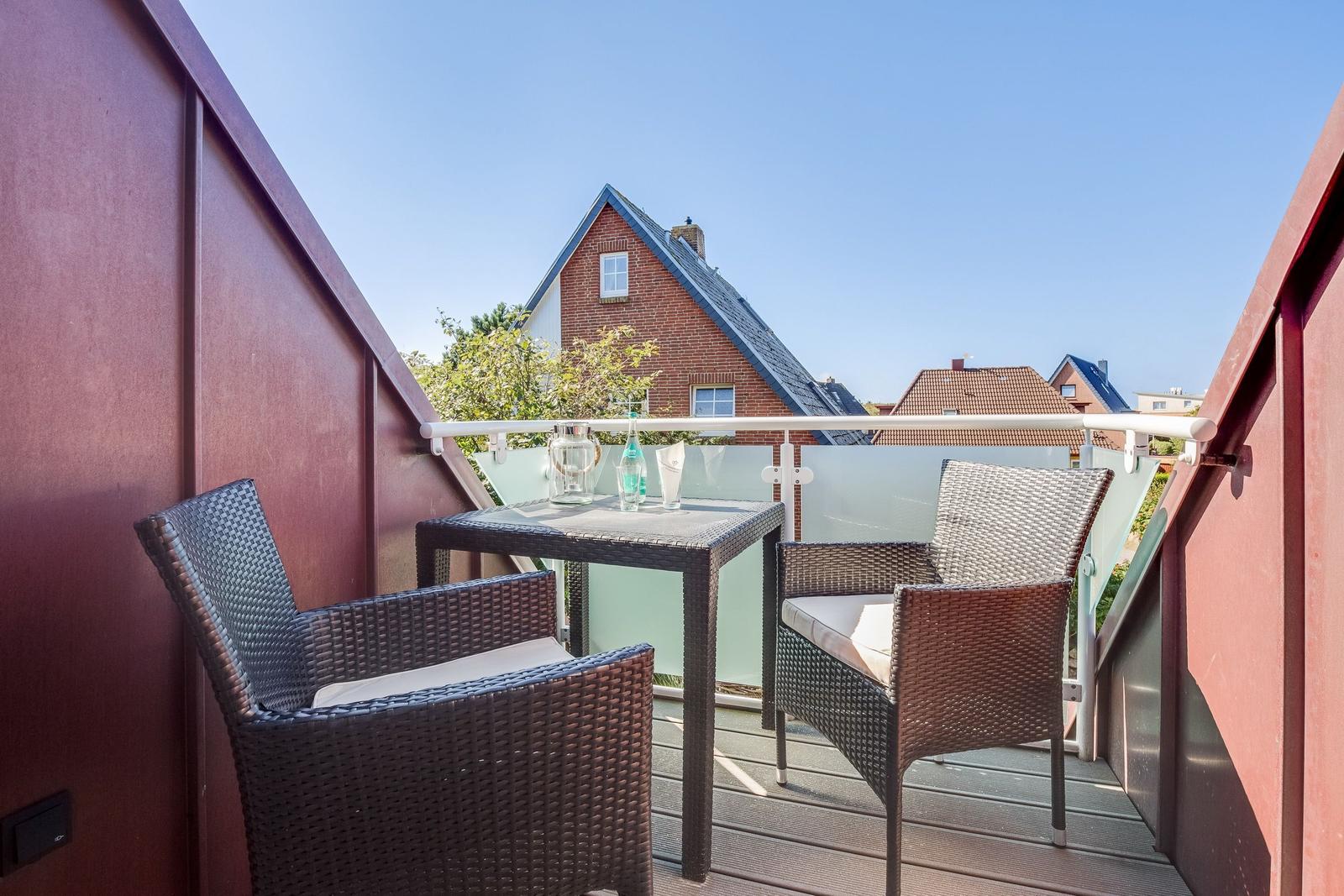 Terrace with table and two chairs, view of residential houses.