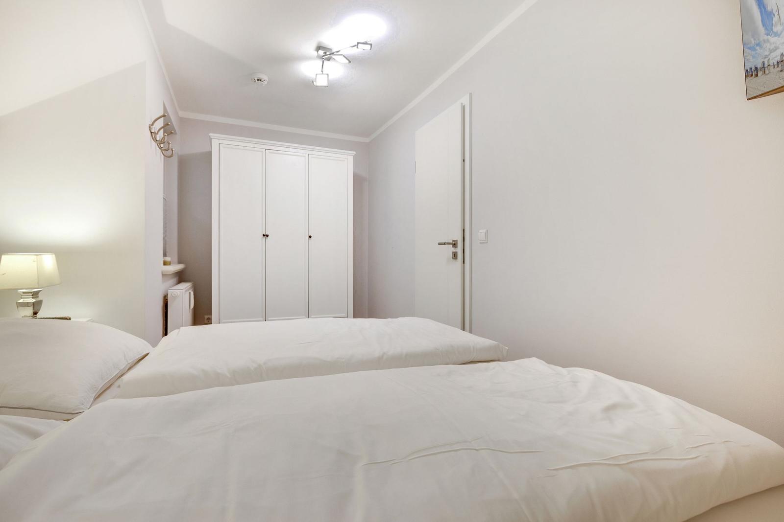 Schlafzimmer mit Doppelbett, Kleiderschrank und Lampe.