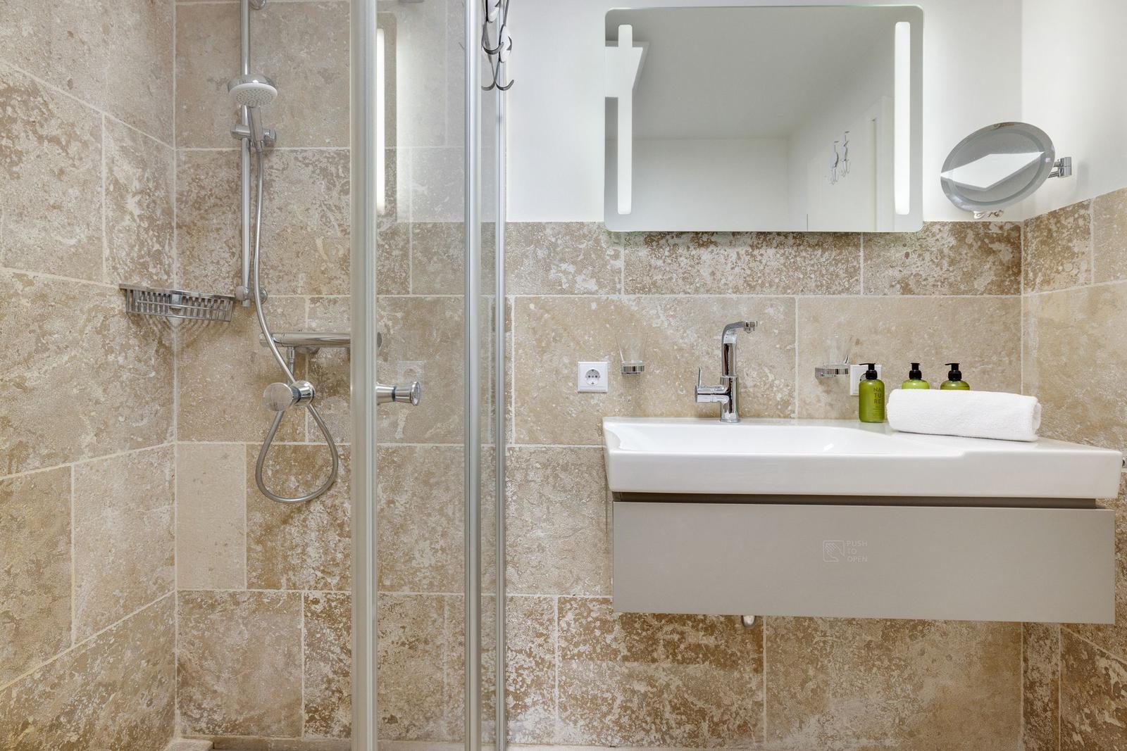 Badezimmer mit Dusche, Waschbecken und Spiegel