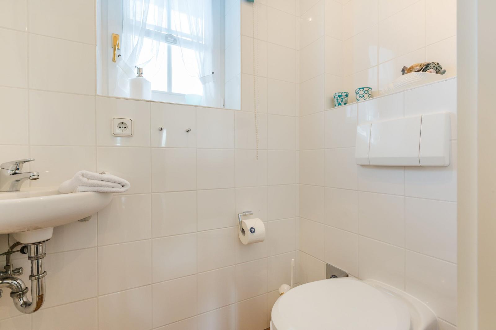 Badezimmer mit Toilette, Waschbecken und Fenster