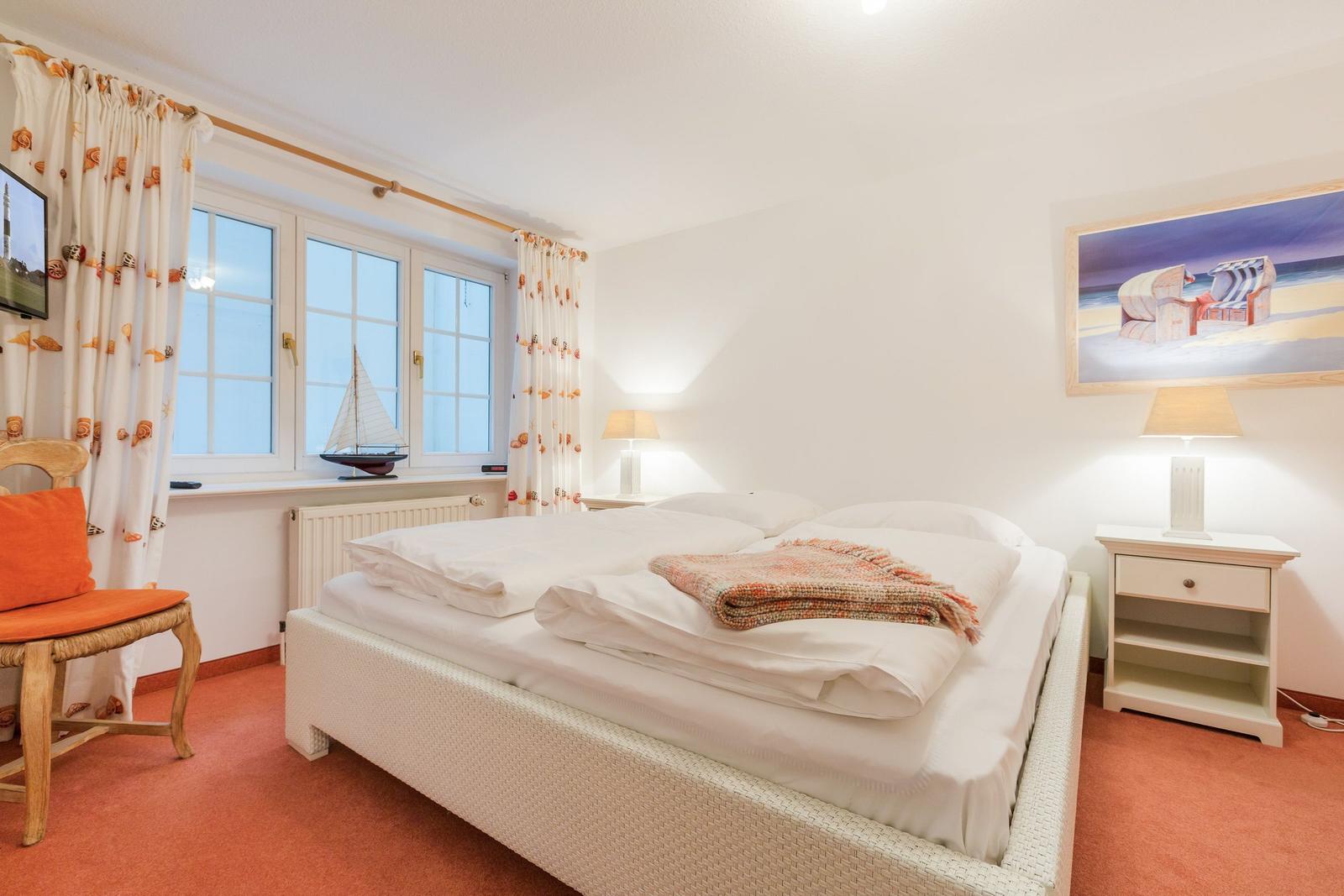 Schlafzimmer mit Bett, Nachttisch, Fenster und Vorhang.