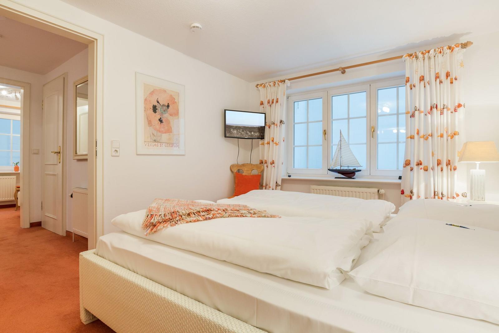 Schlafzimmer mit Doppelbett, Fenster und Vorhang. Wandbild und TV angebracht.