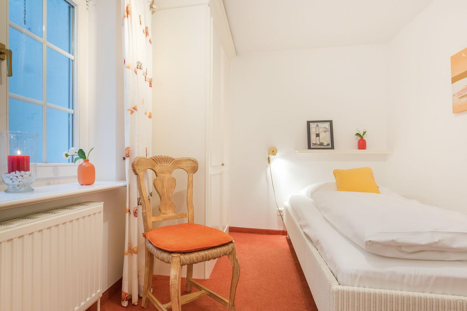 Ein Schlafzimmer mit einem Bett, einem Stuhl und einem Fenster.