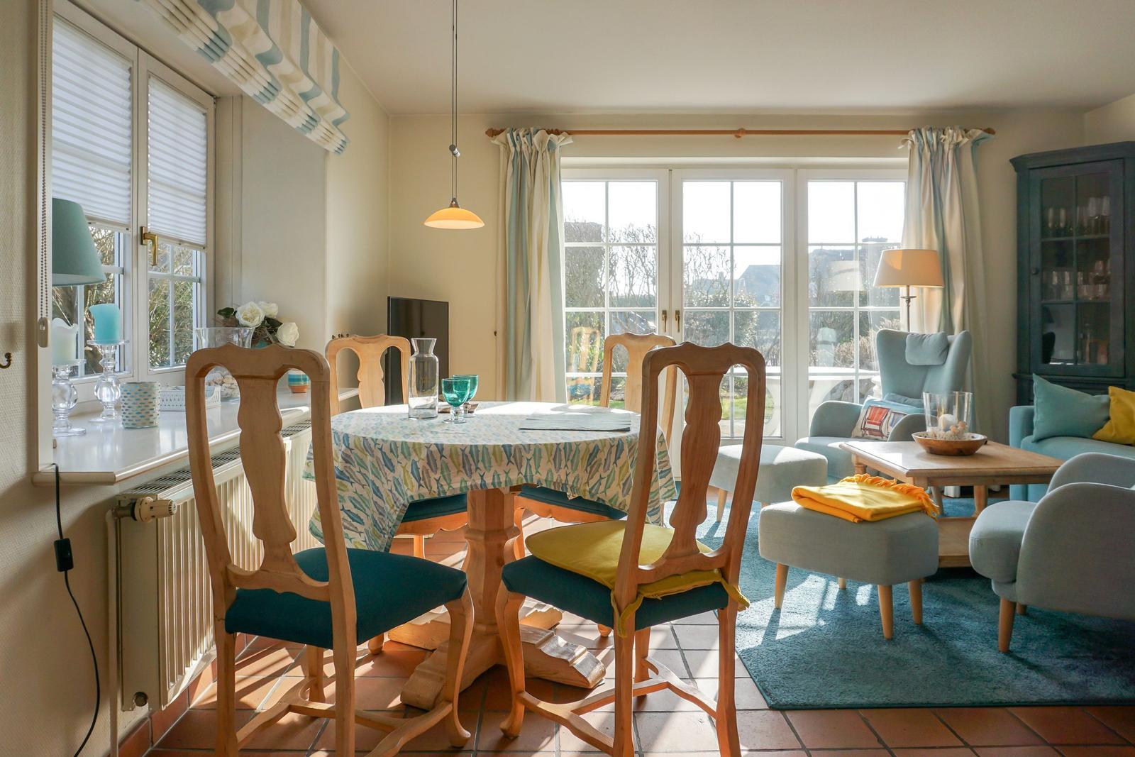 Esszimmer mit runden Tisch und Stühlen, Wohnbereich mit Sofa und Fenster.