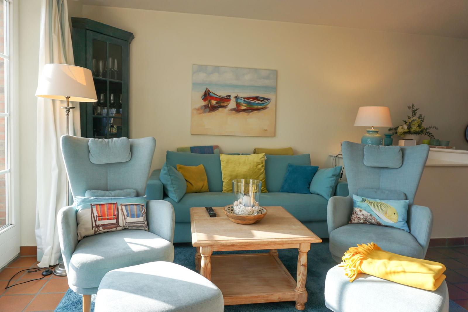 Ein Wohnzimmer mit blauem Sofa, zwei Sesseln und einem Holztisch.
