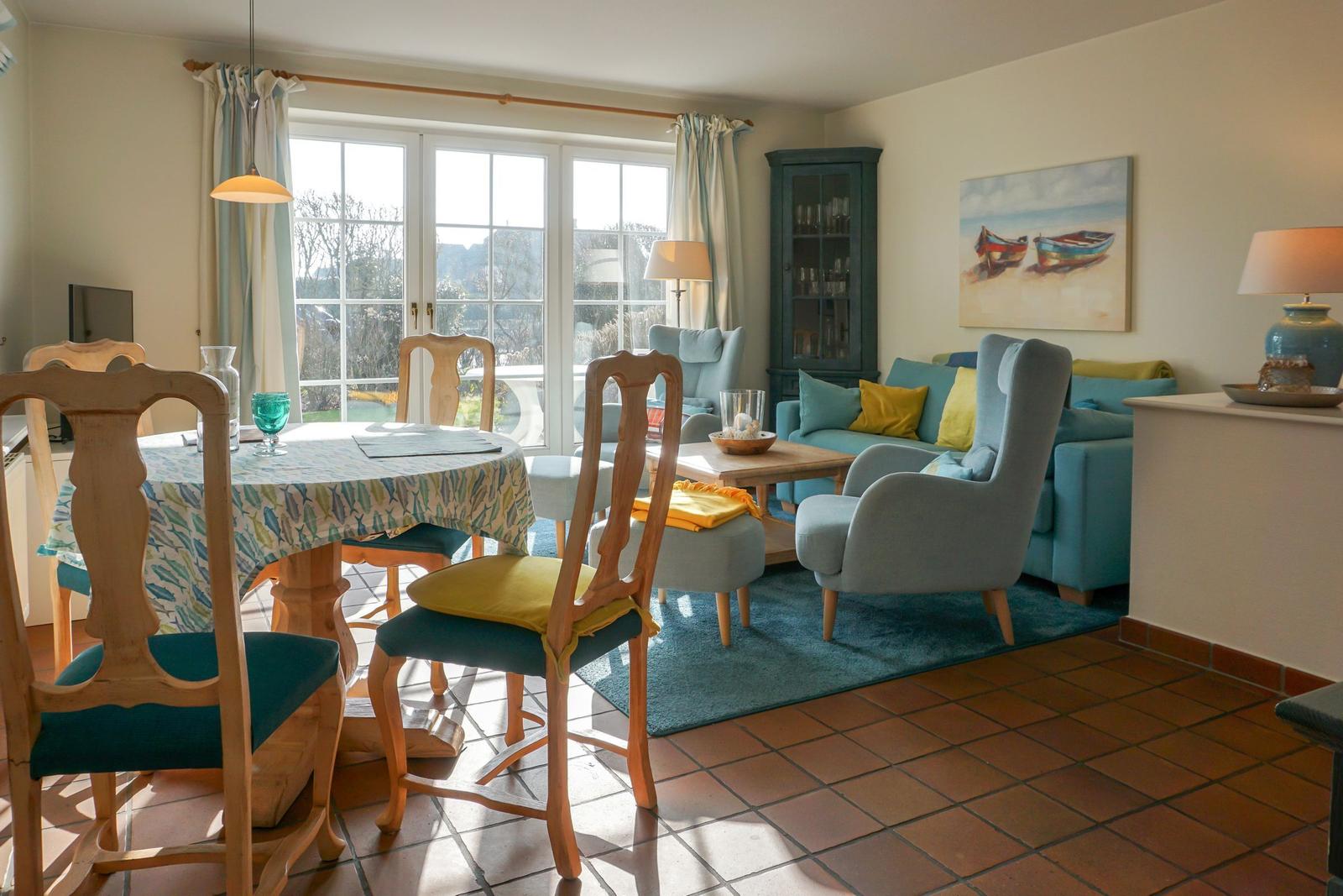 Esszimmer und Wohnbereich mit Holztisch, Stühlen und Sofa. Fenster mit Blick auf Garten.