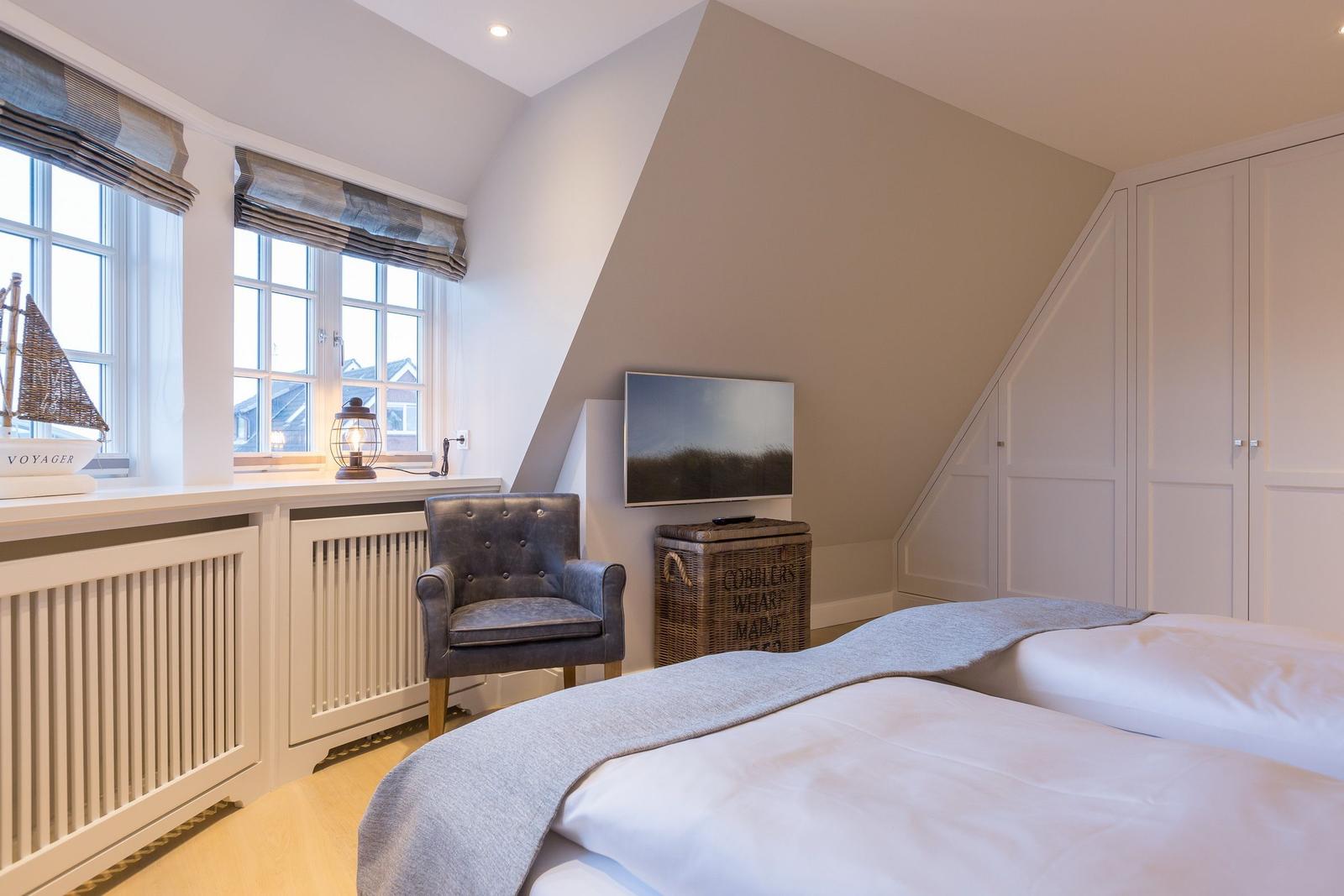 Schlafzimmer mit Doppelbett, Sessel, TV und Fenster mit Blick.