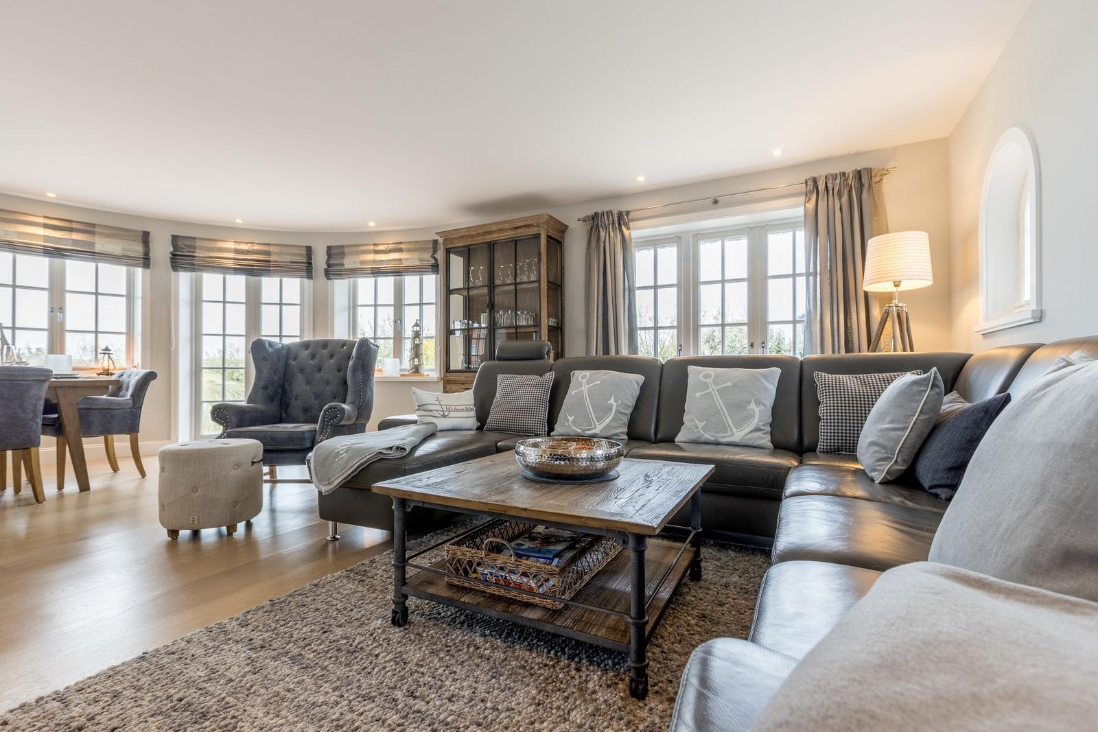 Großes Wohnzimmer mit Sofa, Couchtisch und Fenstern.