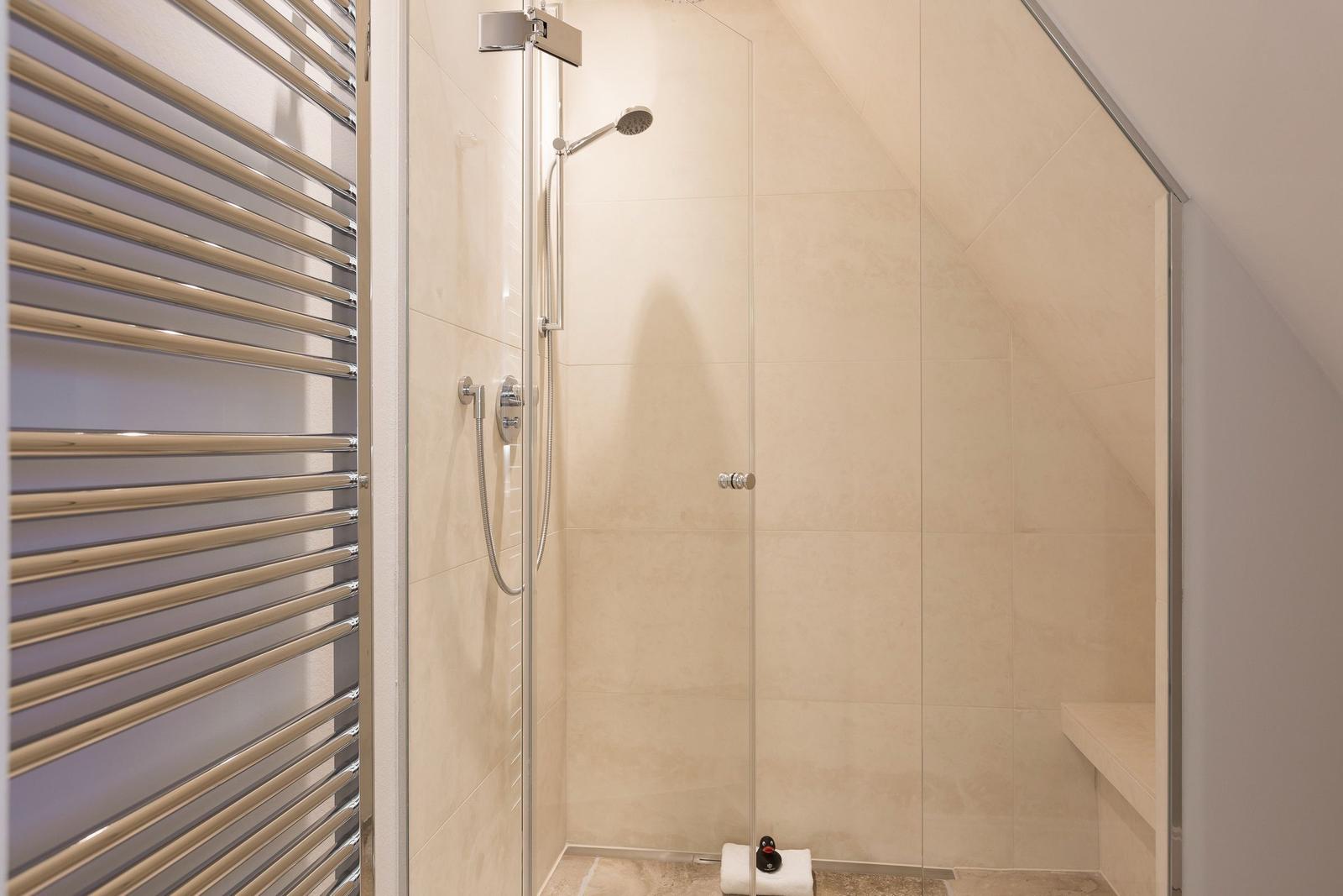 Dusche mit Glaswand, Duschbrause und Heizkörper