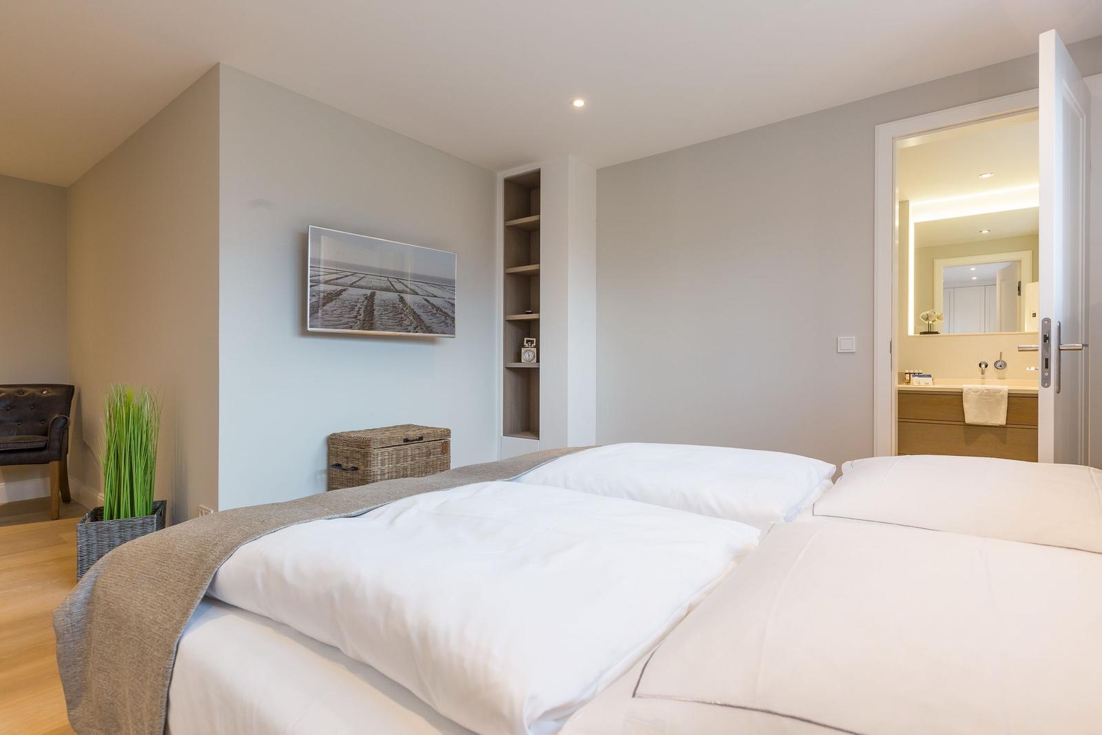 Schlafzimmer mit Doppelbett, Wandbild und Blick in das Badezimmer.
