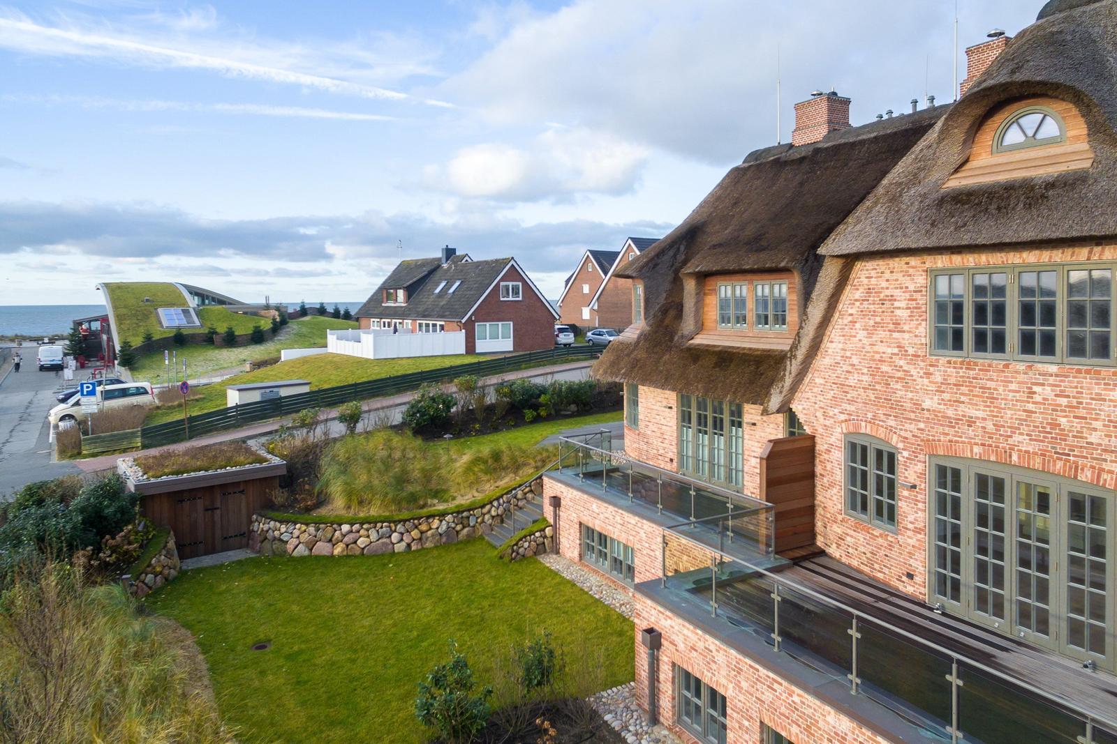 Haus mit Strohdach und Terrasse, Grünfläche und Blick aufs Meer.