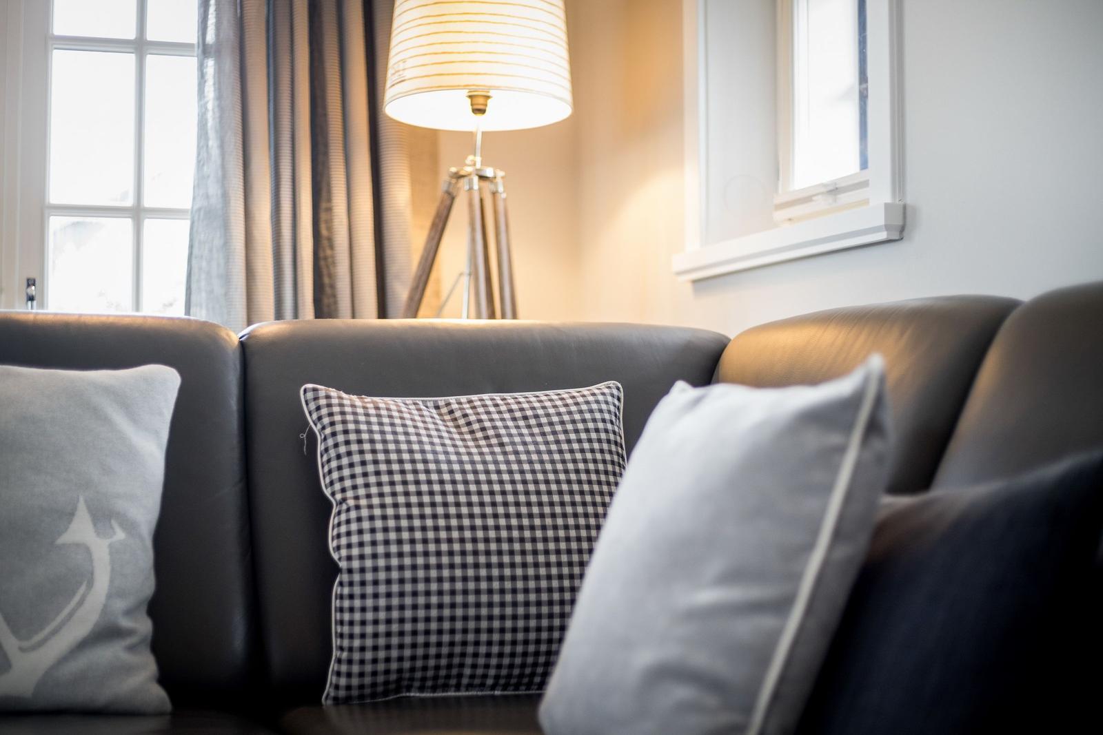 Ein Sofa mit Kissen und einer Stehlampe vor einem Fenster.