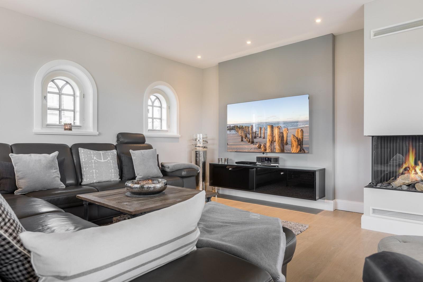 Wohnzimmer mit Sofa, Fernseher und Kamin