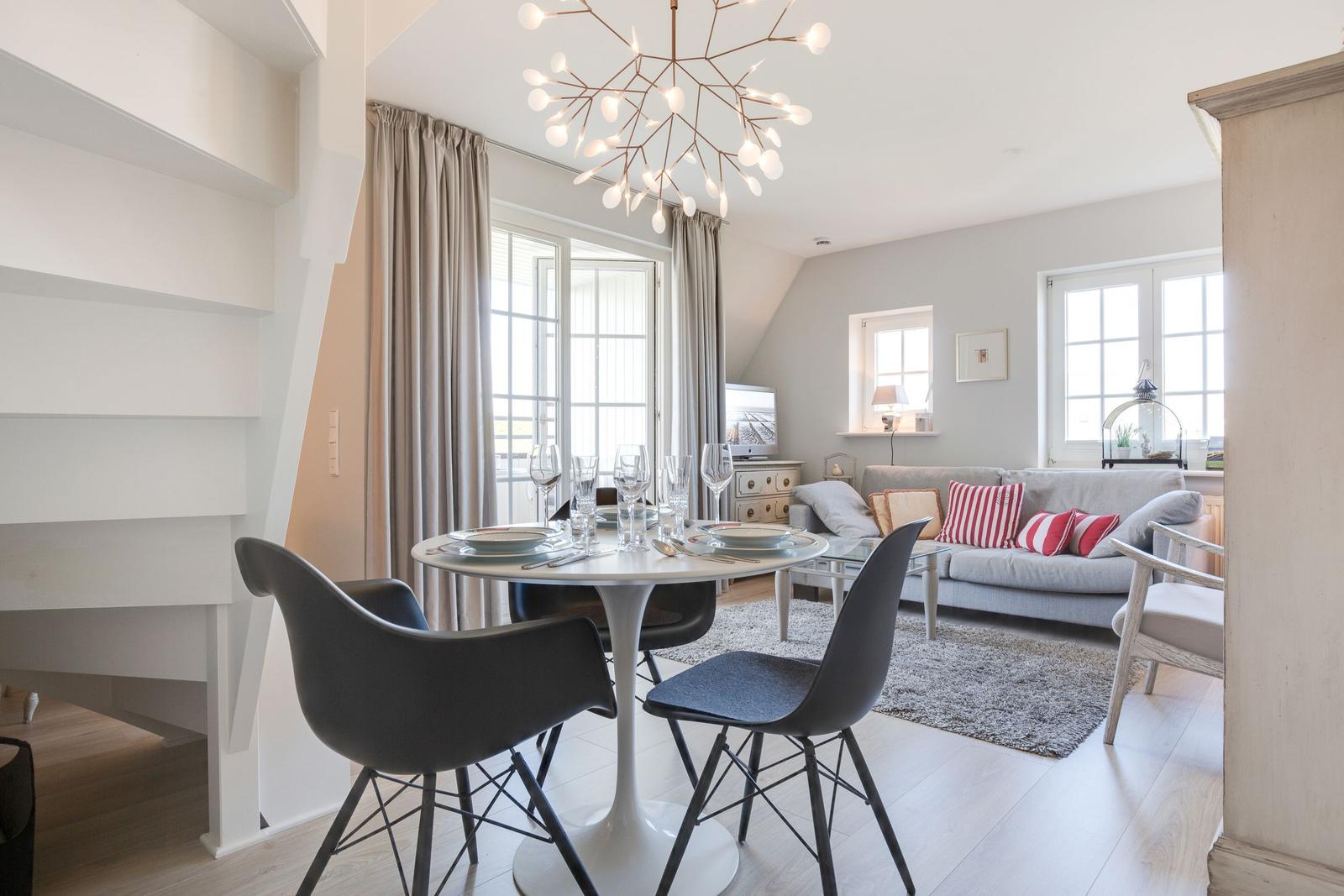 Dining area with table and chairs. Living area with sofa and windows.